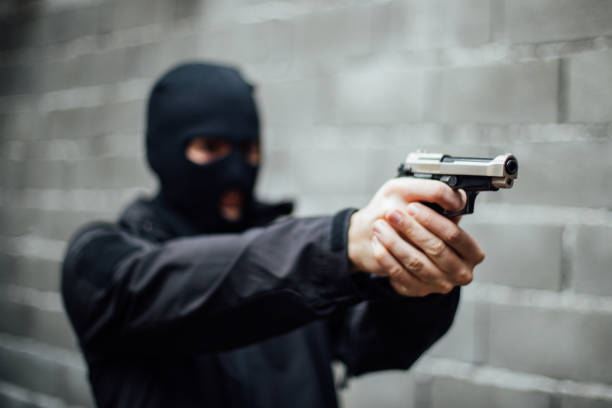 istock A man with a mask on pointing a gun at a target 895042134