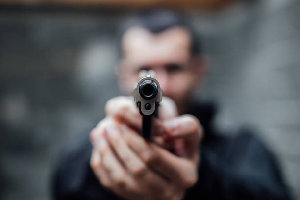 un homme braqué un fusil sur la lentille - gun handgun violence kidnapping photos et images de collection