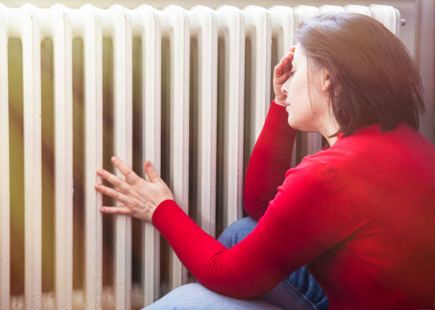 woman with a headache touching radiator stock photo