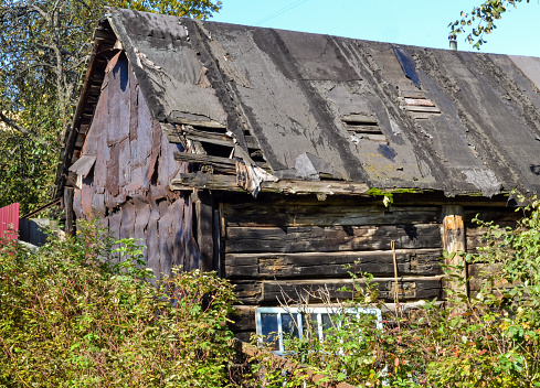Old collapsing black barn with a leaky roof