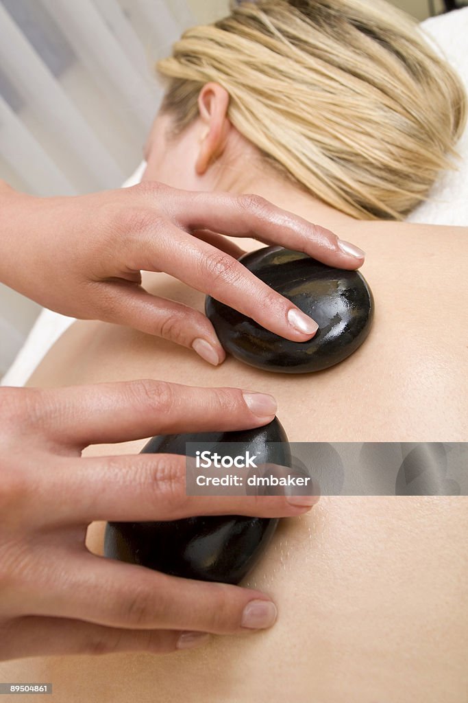 Donna con pietre calde massaggio al centro benessere - Foto stock royalty-free di Adulto