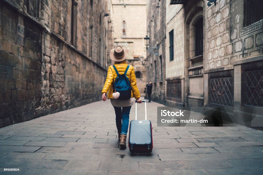 Tourist visiting Spain Young woman with suitcase walking at the street in Barcelona Travel Stock Photo