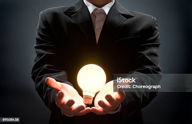 A Businessman With A Lit Lightbulb In His Hands Stock Photo - Download Image Now - Achievement, Adult, Bright