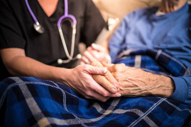 hospice nurse visiting an elderly male patient - holding hands human hand senior adult consoling imagens e fotografias de stock