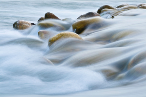 Smooth silky water rushing over rocks in a river.