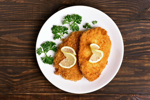 Schnitzel on plate, top view Chicken schnitzel on plate over wooden background. Top view, flat lay breaded photos stock pictures, royalty-free photos & images