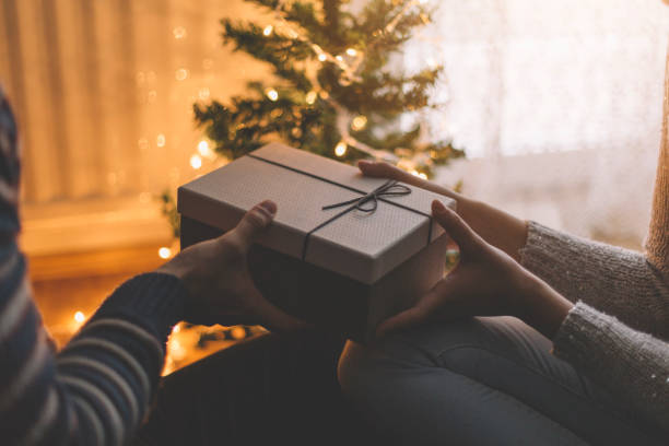 istock Couple exchanging gifts in a room under christmas tree with lights. 895114192