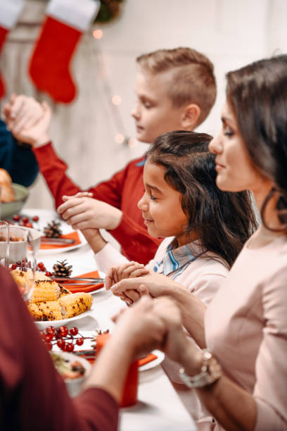 istock family praying before christmas dinner 895114484