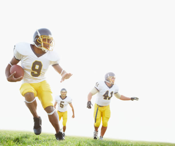 Three American Football players in full tackle football pads stand as a team ready to play. Image taken in Utah, USA.