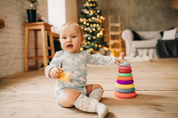 istock Little baby boy sits on plank floor and plays. 895127316