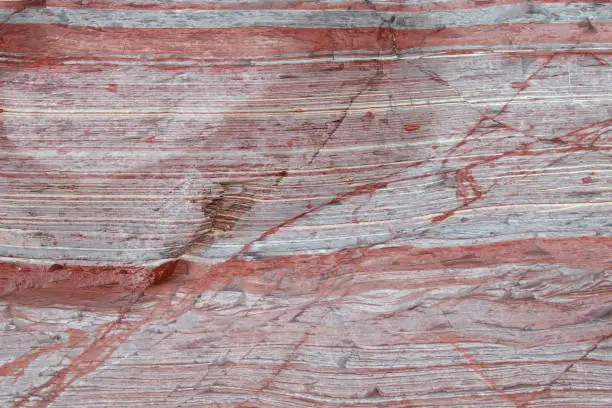 Photo of Red sediment layers in a rock formation.