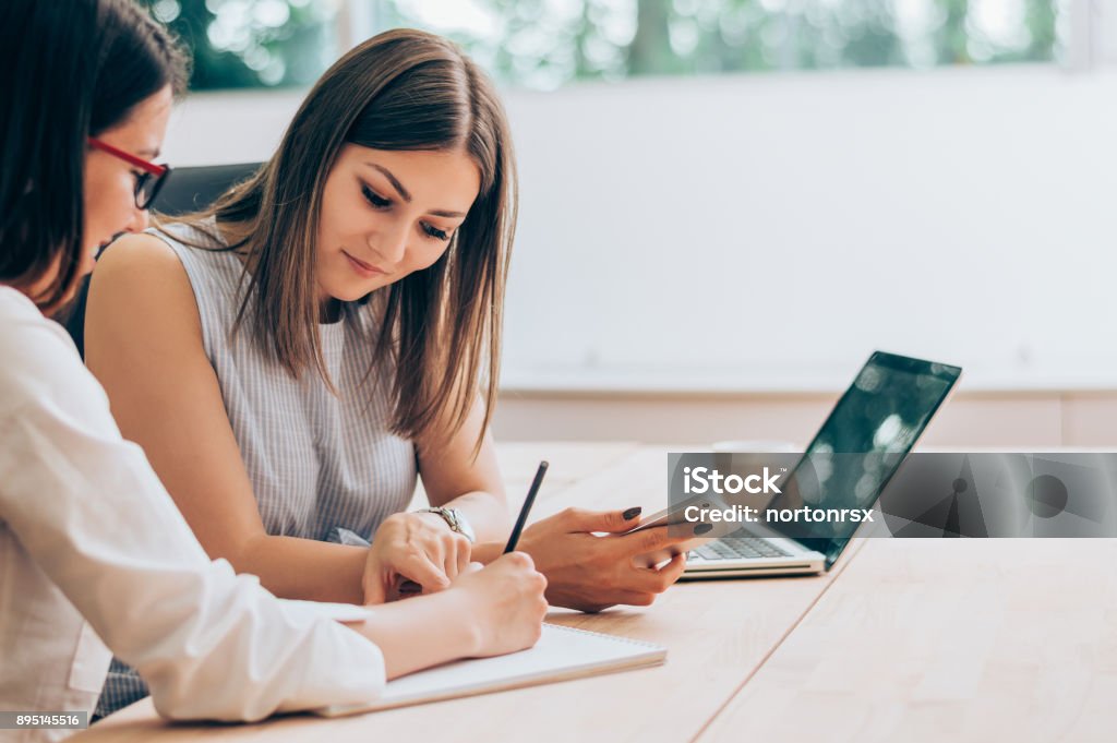 Two female colleagues in office working together. Advice Stock Photo