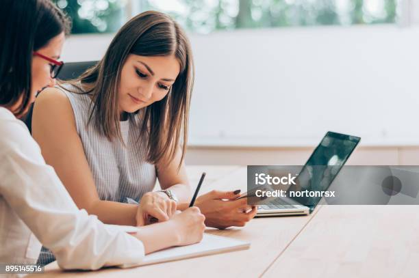 Two Female Colleagues In Office Working Together Stock Photo - Download Image Now - Advice, Business, Two People