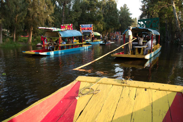 Xochimilco trajineras Xochimilco, Mexico City, Mexico - 2017: People navigate on trajineras (a local type of boat) at the city canal on a Sunday evening. trajinera stock pictures, royalty-free photos & images