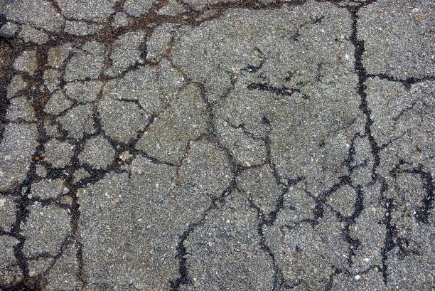 istock texture of gray asphalt with cracks on the road 895242134