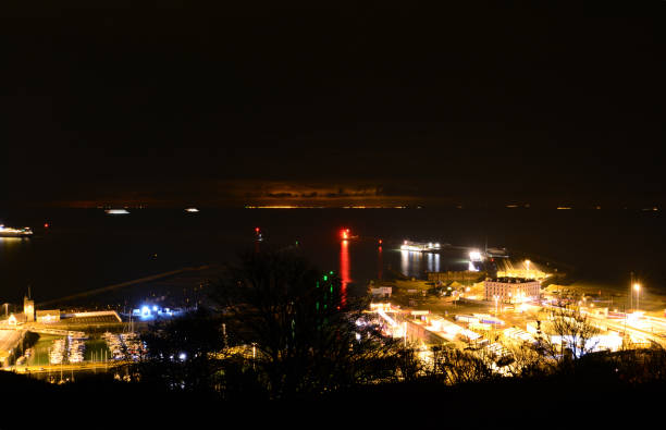 Dover Port and Marina at Night The Port of Dover in Kent, UK, illuminated at night with Calais, France in the background. ferry dover england calais france uk stock pictures, royalty-free photos & images