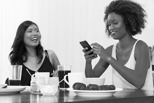 Two your mixed race women at breakfast table monochrome image
