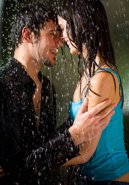 Young amorous happy couple embracing at summer rain stock photo