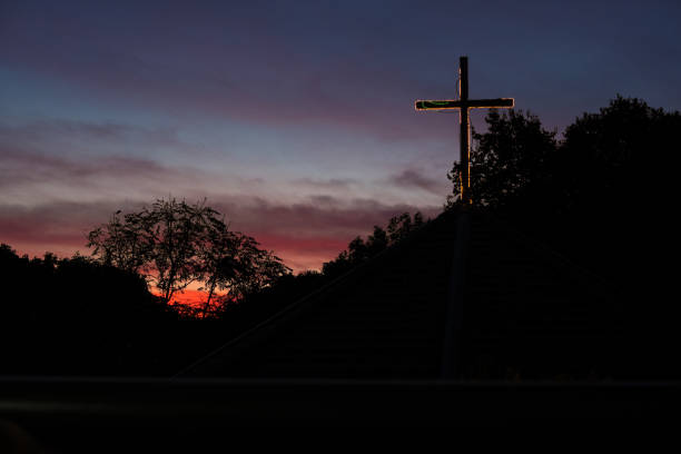 istock silhouette cross on church roof with dramatic sky at dawn. 895263376