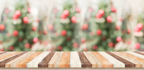 istock Empty rustic wood plank table top with abstract blur christmas tree red decor ball and snow fall background with bokeh light,winter Holiday backdrop,Mock up banner for display of product or promotion. 895263442