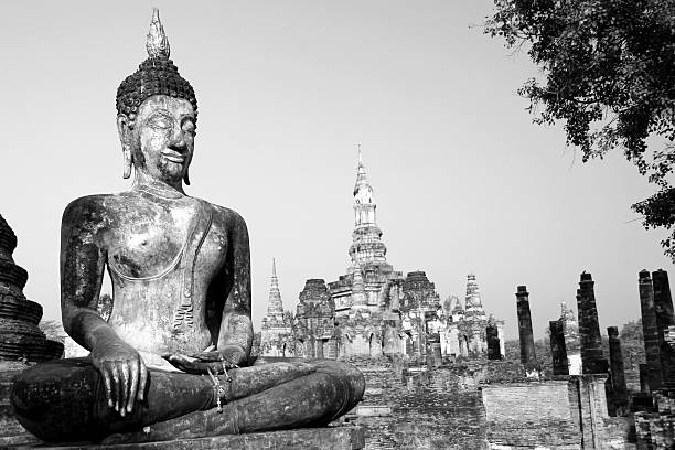 Buddha sculpture at sunrise, Sukothai, Thailand. Wat in background