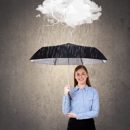 Portrait of businesswoman holding umbrella protecting herself from rain storm