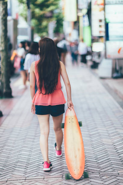 istock Young Woman Walking With Her Skateboard 895379120