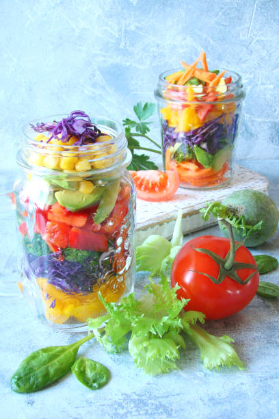 istock vegetable salad with cauliflower, peppers, broccoli, corn in glass jar on blue background 895384418
