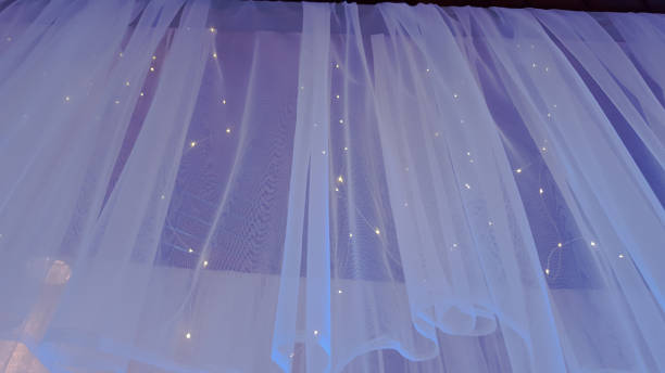 istock Illuminated LED icicle light against sheer fabric background 895384552
