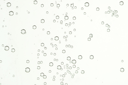Many small shiny air bubbles over a light background