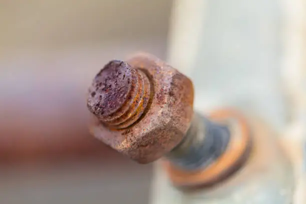 Photo of Close-up image of old rusty screw and bolt on steel surface with blurred background