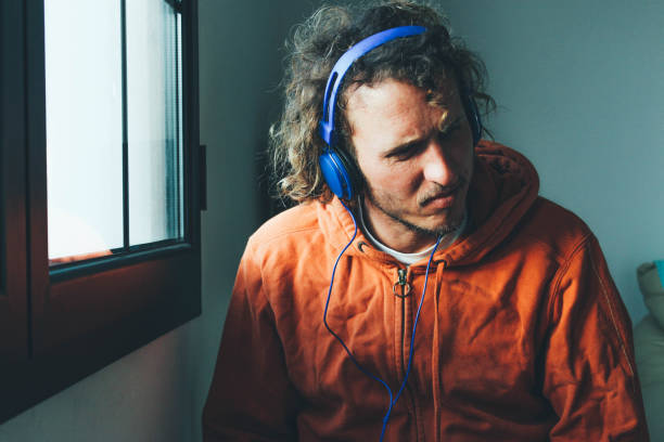 istock Men sitting by the window listening to podcast 895437980
