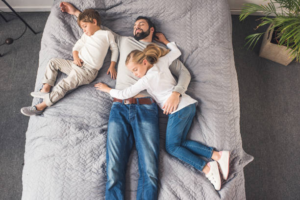 istock family sleeping on bed 895440432