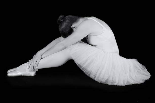 istock Female dancer sit on floor looking sad in artistic conversion black and white 895451476