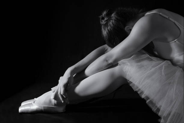 istock Female dancer sit on floor looking sad in artistic conversion black and white 895451750