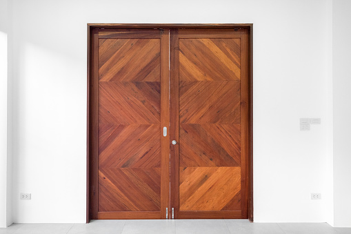 Brown double wood door on white wall background