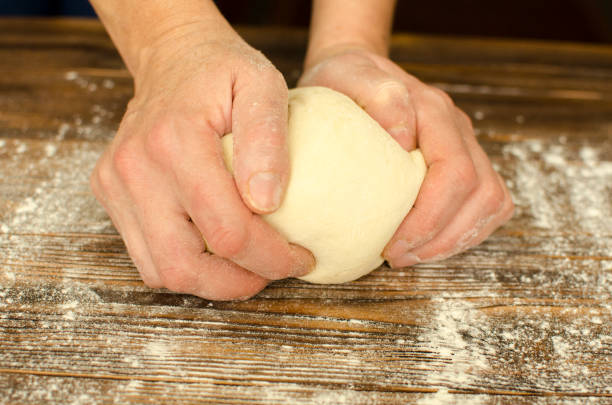 istock Hands knead the dough on wooden background 895497828