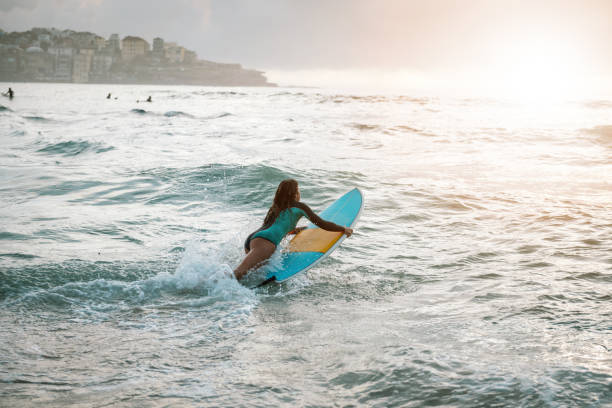istock Woman surfer jumps on her surfboard in the wave 895507772