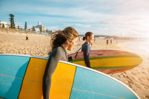 Female surfers rushing to catch a waves Surfing is a way of living in Australia and young and mature sporty women go surfing every morning. sports training australia stock pictures, royalty-free photos & images