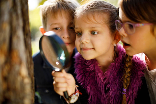 bambini con lente d'ingrandimento - searching child curiosity discovery foto e immagini stock