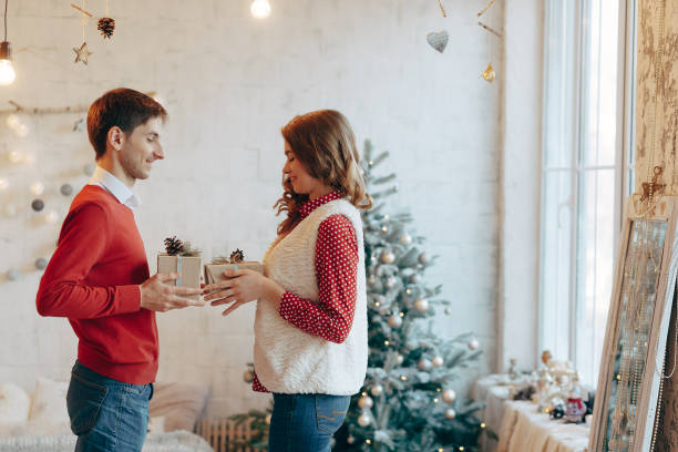 istock Young couple give Christmas presents to each other 895534150