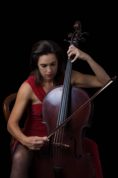 istock Beautiful brunette playing a cello with selective light in red dress 895557014