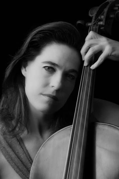 istock Beautiful brunette playing a cello with selective light in red dress artistic conversion 895557086