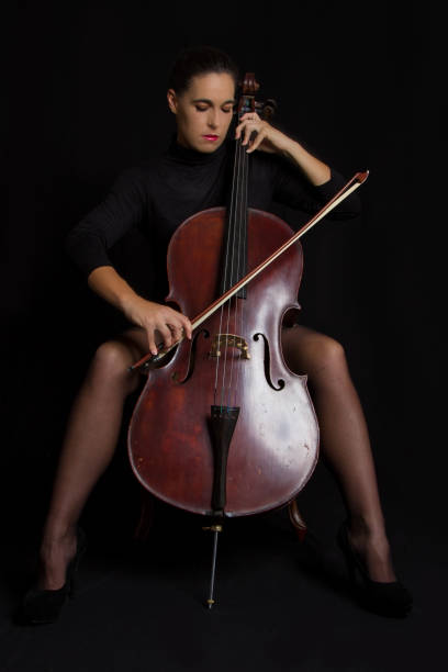 istock Beautiful woman playing a cello with selective light in black dress 895557870