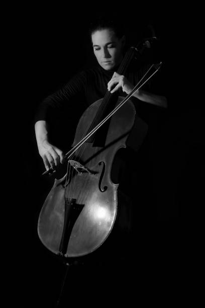 istock Beautiful brunette playing a cello with selective light in black dress artistic conversion 895561522
