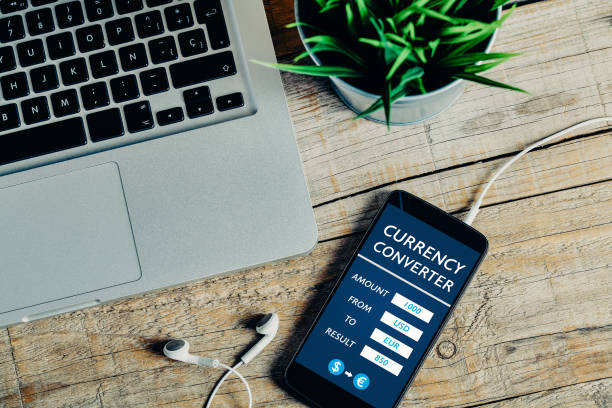 istock Currency converter mobile app service in a mobile phone screen, over a wooden table 895576870