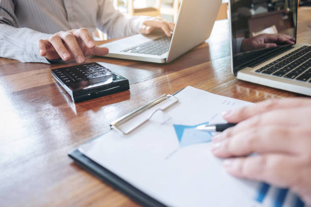 istock Two business persons working at office desk and discussing using laptop to ideas of project about company offer, they is pointing on a contract and giving explanations, team of successful people 895587176