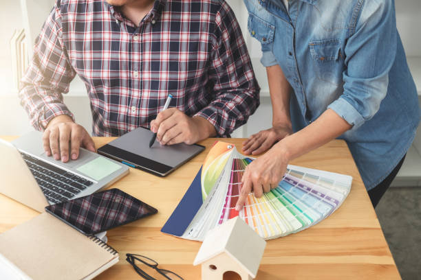 istock Young colleagues designers working together on a creative project and color samples for selection, Color swatch samples, Brainstorming Planning Partnership, creative graphic design working desktop 895587180