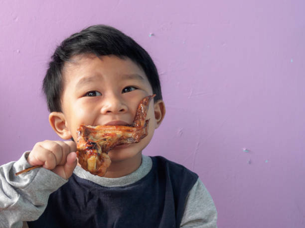 asian boy eating. asian boy eating roasted chicken wing. eating child cracker asia stock pictures, royalty-free photos & images