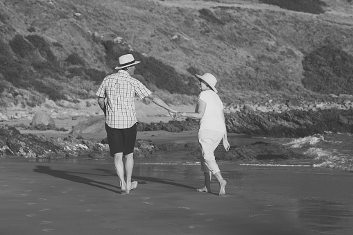 lovely senior mature couple on their 60s or 70s retired walking happy and relaxed on beach sea shore in romantic aging together and retirement husband and wife lifestyle concept